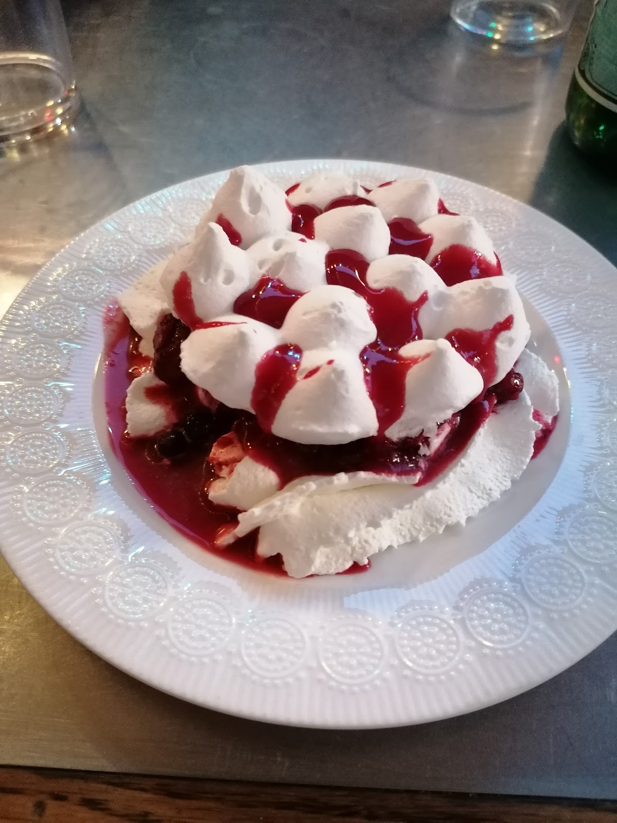 Pavlova aux fruits rouges avec meringue et coulis de baies sur assiette blanche