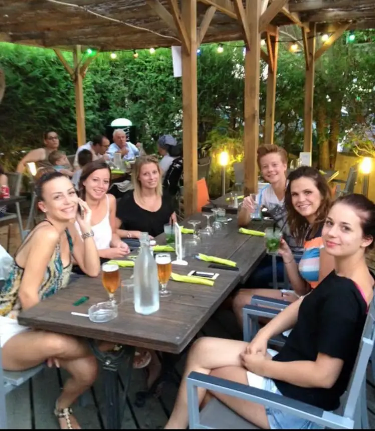 Groupe d'amis attablés en terrasse couverte d'un restaurant le soir