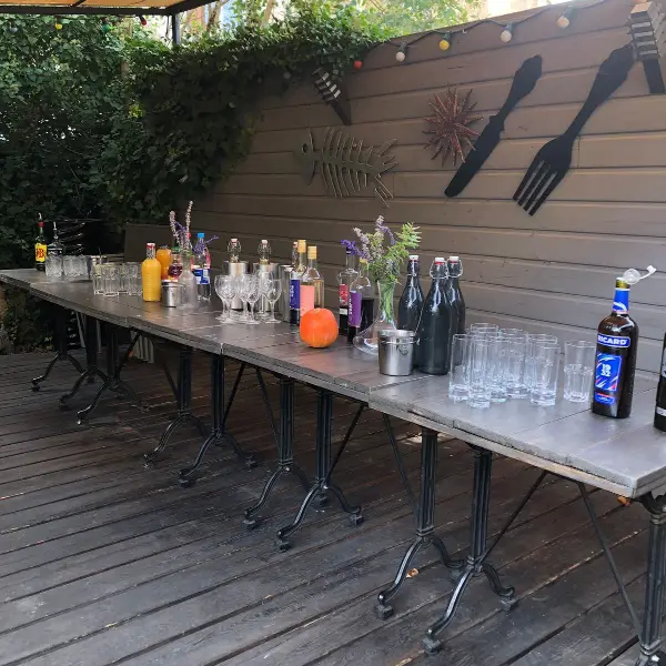 Terrasse de restaurant avec bar en plein air, bouteilles et verres sur longue table en zinc